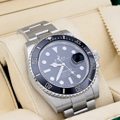 Silver Rolex watch with a blue face on a beige cushion